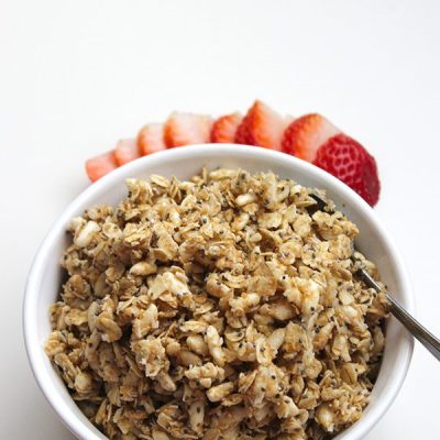 granola in bowl with spoon and strawberries on side