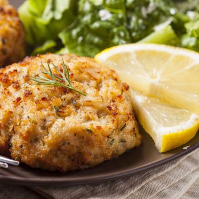 crab cakes on plate with sliced lemons