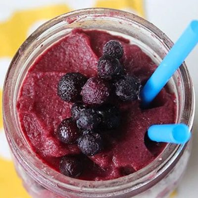berry smoothie in glass with blue straws