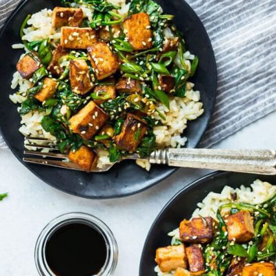 tofu and vegetable stir fry on black plate with fork