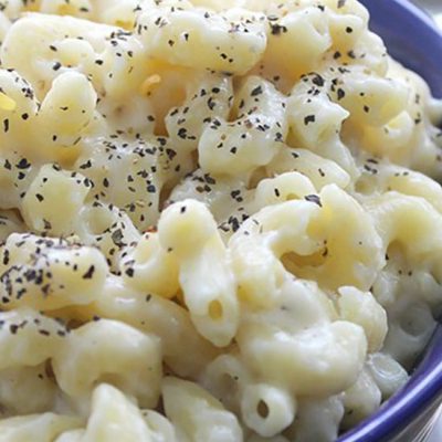 Creamy white mac and cheese sprinkled with black pepper in blue bowl