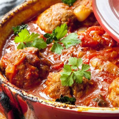 Chicken meatballs with tomato sauce cooking in red pot