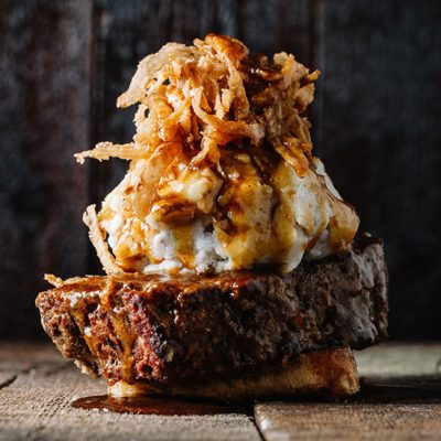 Meatloaf sandwich topped with mashed potato, crispy onions and gravy