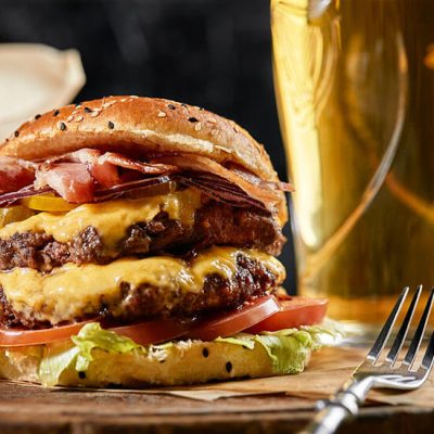 Cheese burger beside glass of beer on counter