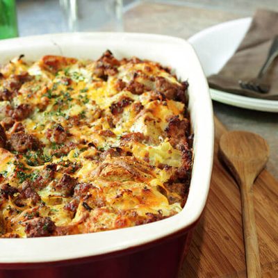 Bread pudding casserole in red and white dish on wood board