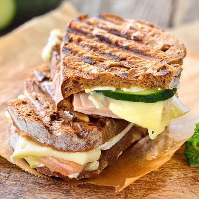 Smoked turkey and melted brie cheese panini on sandwich paper on counter