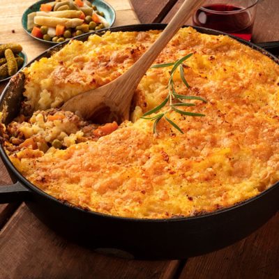 Consumed homemade shepherds pie in iron skillet pan with wood spoon on counter