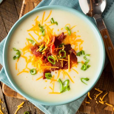 Creamy potato soup sprinkled with parmesan cheese shavings and bacon in bowl