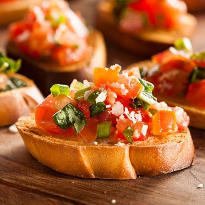 Homemade bruschetta topped with tomatoes, basil, and cheese on counter