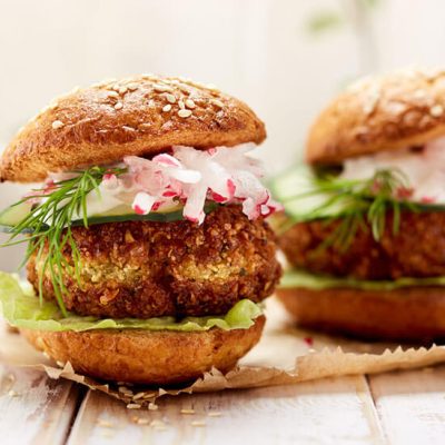 Falafel burgers with lettuce, onion, and cucumber on wood counter