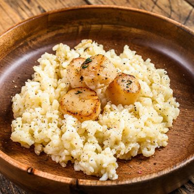 Italian Risotto with scallops in wood bowl on wood counter