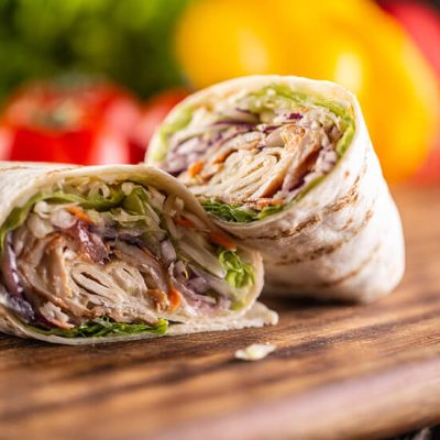 Chicken shawarma wrap with vegetables cut in half on wood board