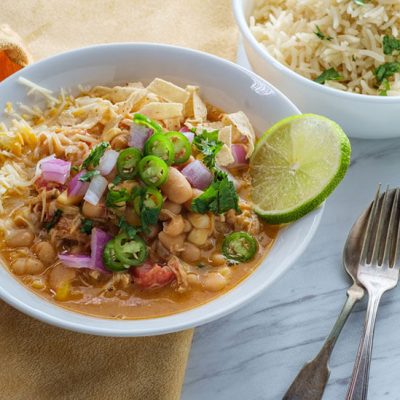White chicken chili with slice of lime, chopped jalapenos and red onions in bowl
